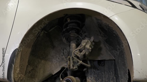 A disassembled wheel with a brake pad and shock absorbers in a car at a service station. A stable image of a disassembled car on a lift for repair in an auto repair shop.