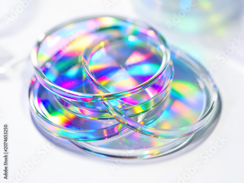 Glass lens discs refracting bright rainbow light with glossy colorful prismatic reflections