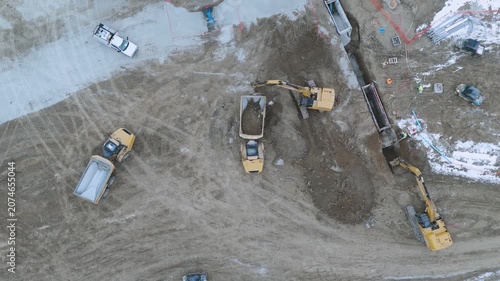 Top down view of hydraulic excavators loading soil into dump trucks