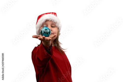 A blue glass Christmas tree ball in the palm of a little girl's outstretched hand, wearing a red dress and a Santa Claus hat. PNG.