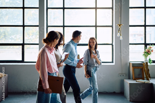 Happy business team talking while walking through office.