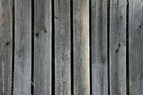 Weathered wooden fence with vertical planks and natural wood grain texture. Rustic background suitable for outdoor and construction themes.