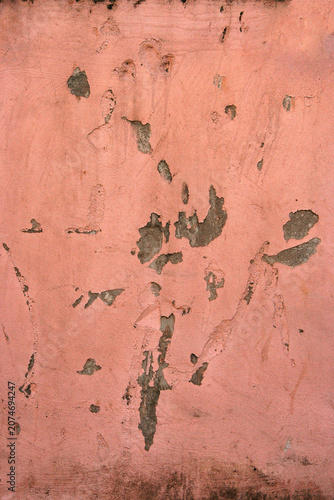 Weathered pink painted wall with peeling paint, stains and aged surface details. Abstract urban texture background with vintage character.