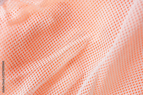 Obraz na płótnie White mesh fabric over bright orange textile creating breathable sports material