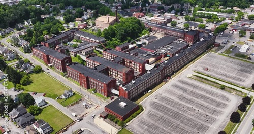 LLION, NY, USA - June 24, 2026: Afternoon summer aerial video of downtown, business district, LLION, NY.  Former Remington Arms factory brick building.