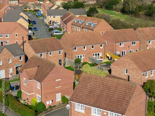 Aerial drone photograph overlooking modern residential housing in the village of Tockwith near York in North Yorkshire showing brick family homes gardens quiet streets and surrounding countryside