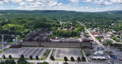 LLION, NY, USA - June 24, 2026: Afternoon summer aerial video of downtown, business district, LLION, NY.  Former Remington Arms factory brick building.