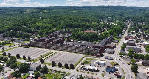 LLION, NY, USA - June 24, 2026: Afternoon summer aerial video of downtown, business district, LLION, NY.  Former Remington Arms factory brick building.