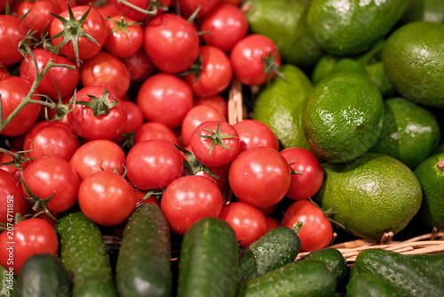Fresh cucumbers, tomatoes and avocados on display in a supermarket produce section