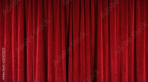 Red curtains cover a stage in a theater preparing for a performance in the evening