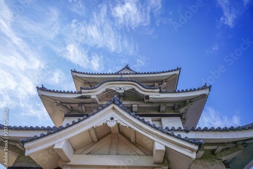 青空に映える日本の伝統的な城の天守閣 ローアングルからの迫力ある城郭建築 観光イメージ