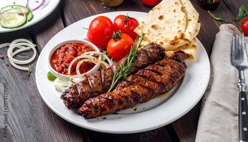 Delicious Grilled Kebab Platter with Fresh Vegetables and Flatbread.