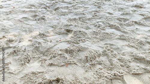 Photography Detailed close-up view of wet beach sand surface showing natural textures, ripple patterns, and small mounds created by water and wind