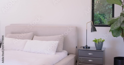 Camera is starting pan left from window revealing bed, duvet, pillows and lamps to showcase styling