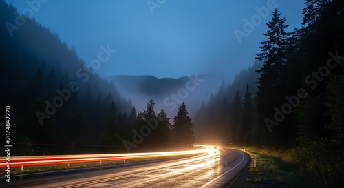 Foggy mountain road at night with light trails and pine trees