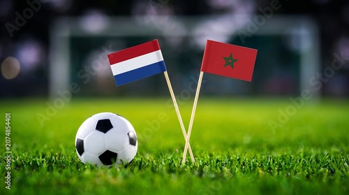 Close-up of soccer ball on grass field with flags of Netherlands and Morocco
