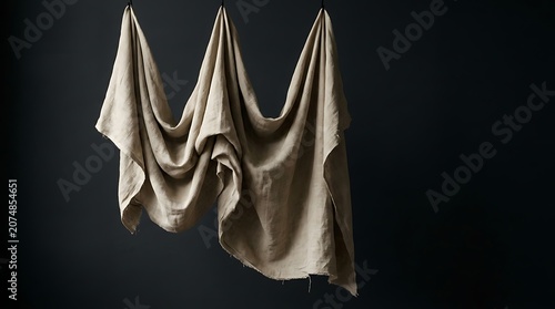 Draped fabric hangs elegantly on a stand in a dark room with candles
