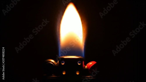 Close-up of a lighter igniting and producing a bright flame in the dark