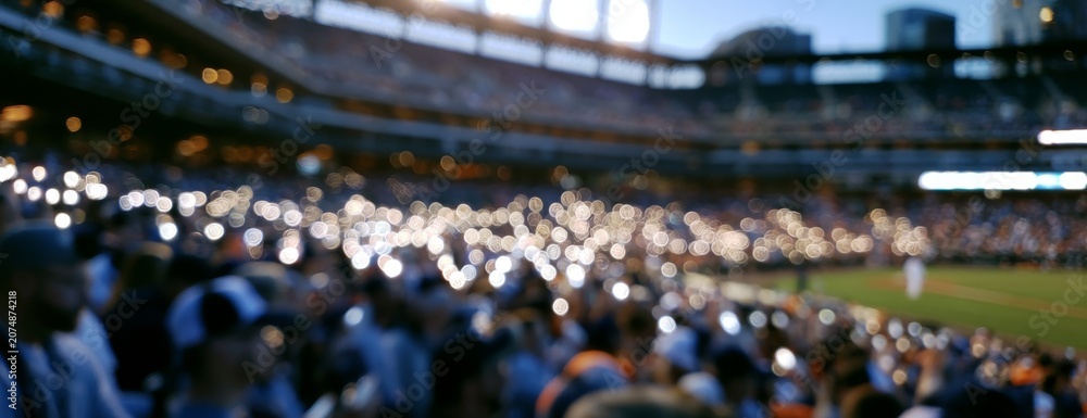 Obraz premium Crowd cheering with phone lights at baseball stadium during night, blurred background