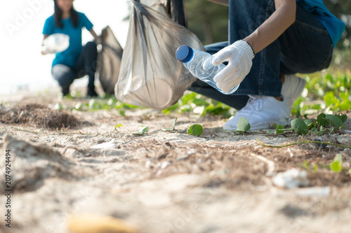 Group of active Asian volunteers cleaning up plastic waste and garbage on the beach together, focusing on environmental conservation and community teamwork.