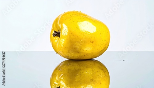 Bright yellow, misshapen fruit with a stem sits on a glossy surface, reflecting