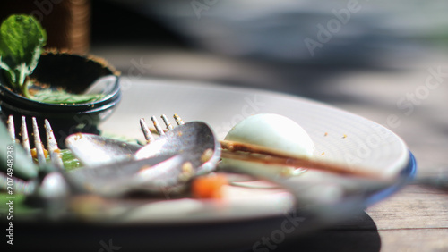 Vászonkép Close-up of a dirty plate with leftover food, hard-boiled egg and used cutlery a