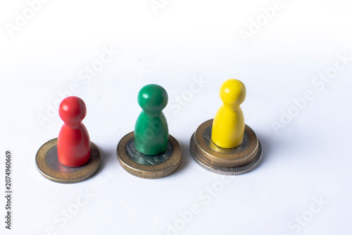 Colorful game pieces standing on coins representing investment, savings and personal finance