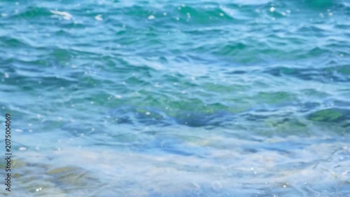 Slow motion close-up of a powerful ocean wave crashing and creating a massive splash of white foam against a vibrant blue sea background