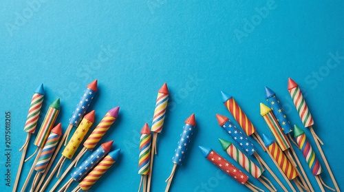 An engaging flat-lay composition featuring a collection of traditional wooden-fused rocket fireworks clustered at the bottom of the frame. The rockets feature decorative paper tubes adorned with vario