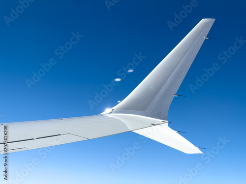 Clear blue sky above airplane wing and tail fin