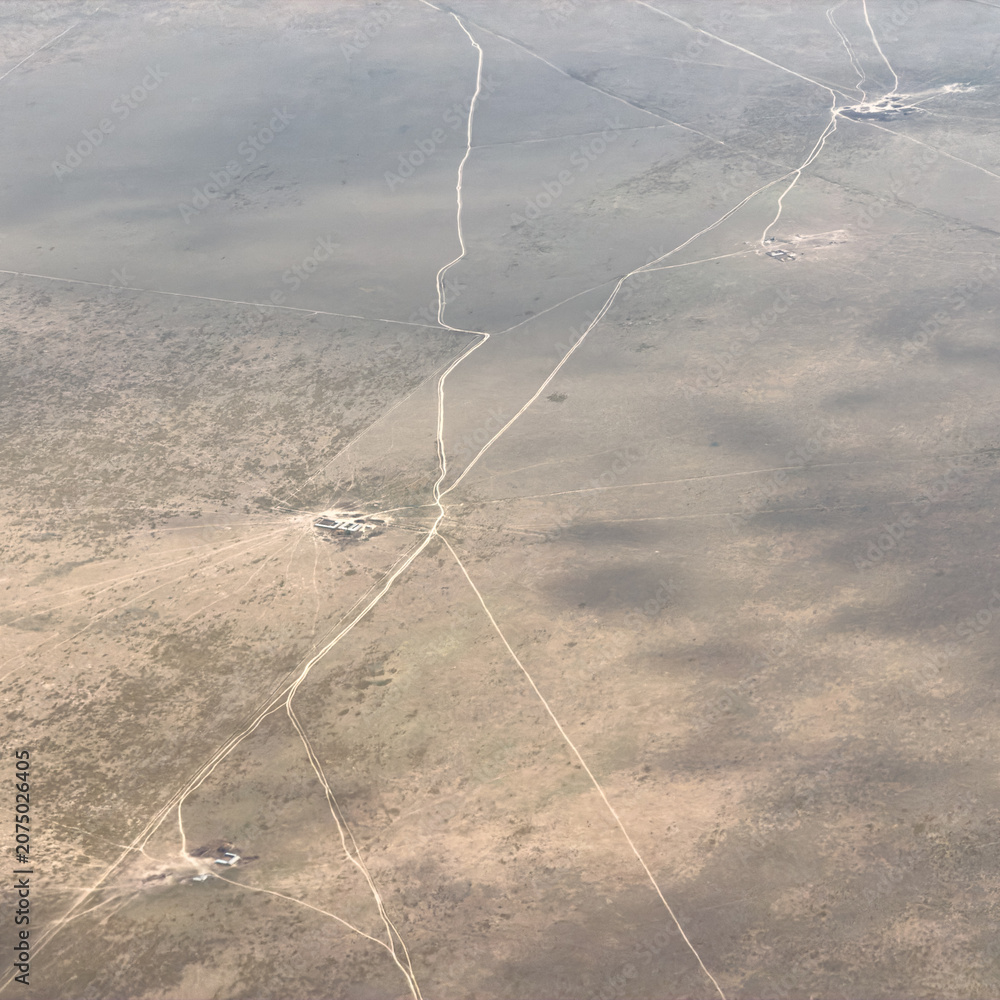 Fototapeta premium Aerial view of vast desert with winding roads and sparse vegetation