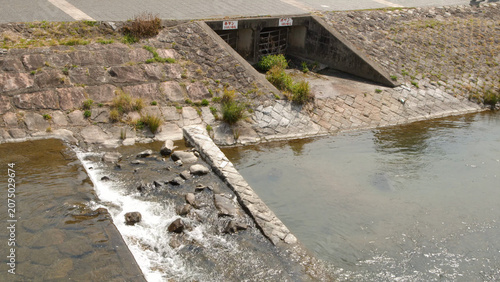 Water Flowing Over Stone Weir at Kamo River Embankment in Kyoto Japan