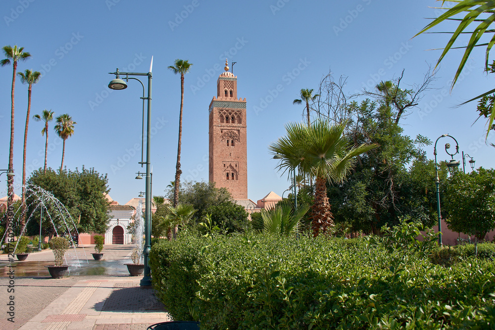 Fototapeta premium The ancient minaret of the Koutoubia Mosque rises majestically above the urban gardens of Marrakech.