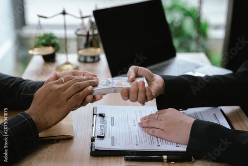 Close-up of a cash payment being handed over during a legal or business meeting, symbolizing financial transactions, settlement, agreement, bribery, corruption, or contract-related payment.