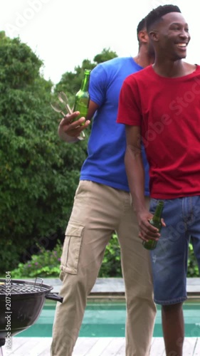 Vertical video: Laughing blue-tee moving in raising beer, tongs on deck hugging red-tee, copy space