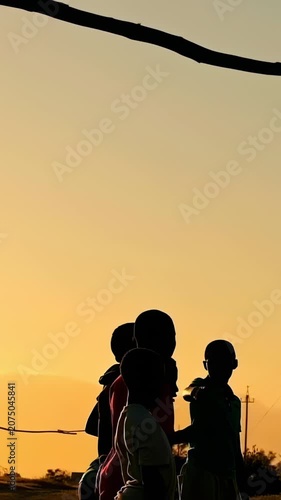 Vertical video: Sunset drawing six boys in tees shifting at field before play with soccer ball