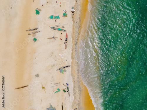 Aerial view of traditional wooden fishing boats and fishermen on the sandy beach in Monrovia, Liberia.