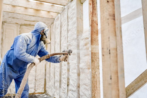 Cuadro en lienzo Worker spraying polyurethane foam insulation onto interior wall of timber frame house
