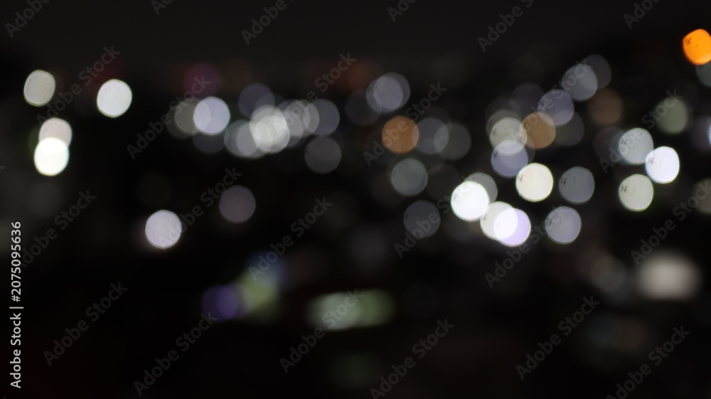 Fototapeta premium Blurred white and orange city lights create an abstract panoramic bokeh with cinematic mood, peaceful ambiance, and refined nighttime elegance.