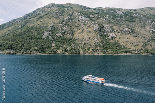 Photography Tourist boat cruising on blue water near green mountain
