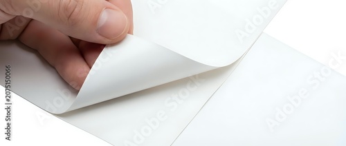 Hand holding corner of blank white paper sheet, peeling back edge to reveal clean surface underneath. Suitable for stationery, office supplies, and design mockup projects.