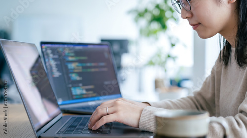 オフィスでパソコンに向かいプログラミングや開発業務をする女性システムエンジニア・SE