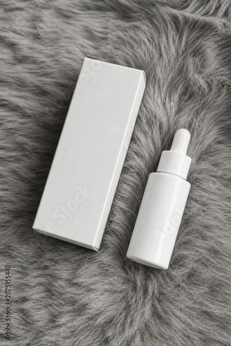 White Cosmetic Serum Dropper Bottle and Blank Packaging Box on Grey Faux Fur Texture