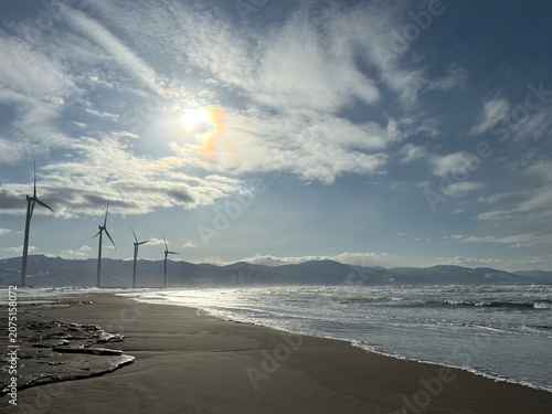Wind turbines along Ishikari Beach under a dramatic sky, Hokkaido, Japan