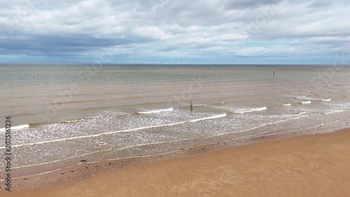 Aerial view of waves at Crosby Beach with offshore wind farm background