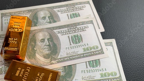 Obraz na płótnie Gold bars resting on US one hundred dollar bills, representing combined investme