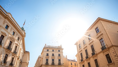 Sunlit afternoon view of light beige limestone buildings under a clear blue sky.