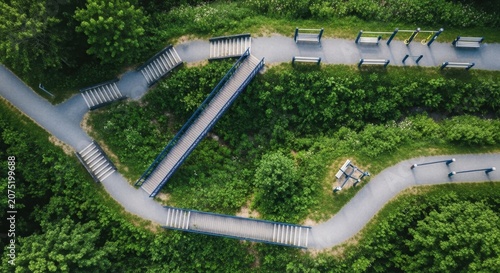 Aerial view of a winding outdoor hiking trail with wooden bridges and benches amidst lush green foliage