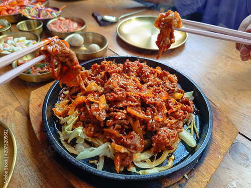 plate of spicy Korean stir-fried meat served on a hot sizzling plate with fresh cabbage and onions, topped with sesame seeds.showcasing authentic Korean cuisine.