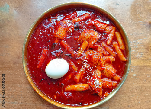 delicious bowl of Korean spicy rice cakes (tteokbokki) served with fish cakes, a boiled egg, and sesame seeds in a rich red chili sauce. 